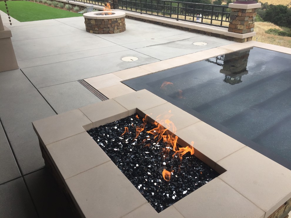 Diseño de piscina infinita minimalista de tamaño medio rectangular en patio trasero con losas de hormigón