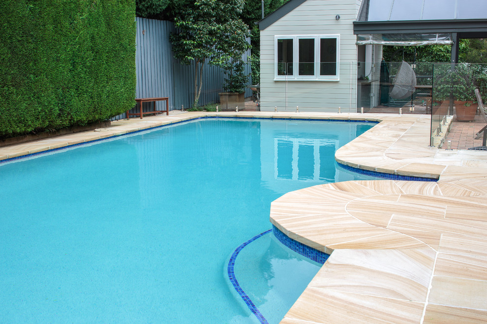 Esempio di un'ampia piscina monocorsia chic rettangolare dietro casa con pavimentazioni in pietra naturale