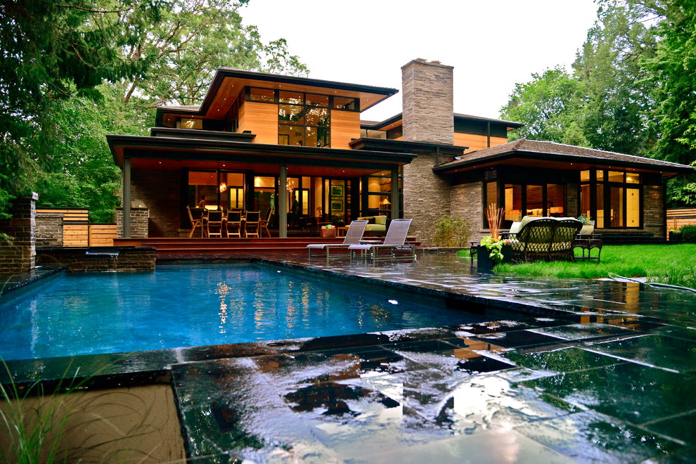 На фото: большой наземный, прямоугольный бассейн на заднем дворе в современном стиле с джакузи и покрытием из каменной брусчатки