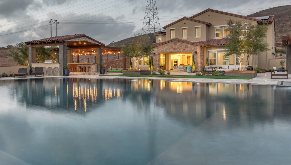 Ispirazione per una grande piscina a sfioro infinito design personalizzata dietro casa con una vasca idromassaggio e pavimentazioni in pietra naturale