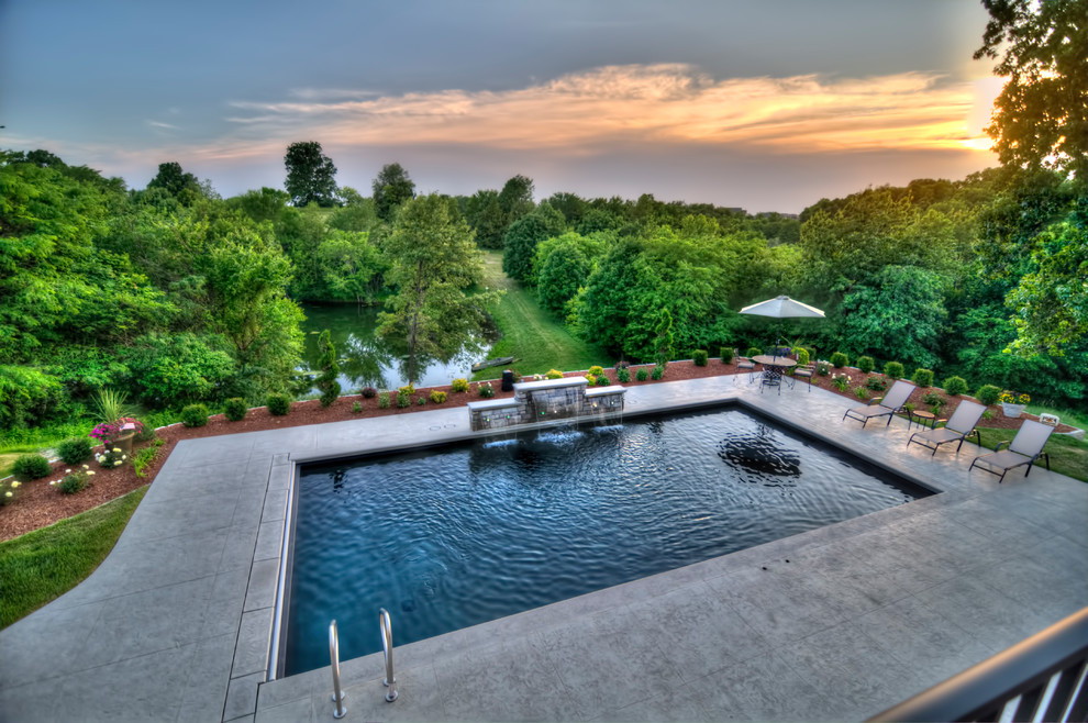 Inspiration for a large contemporary back rectangular natural swimming pool in Cedar Rapids with a water feature and stamped concrete.