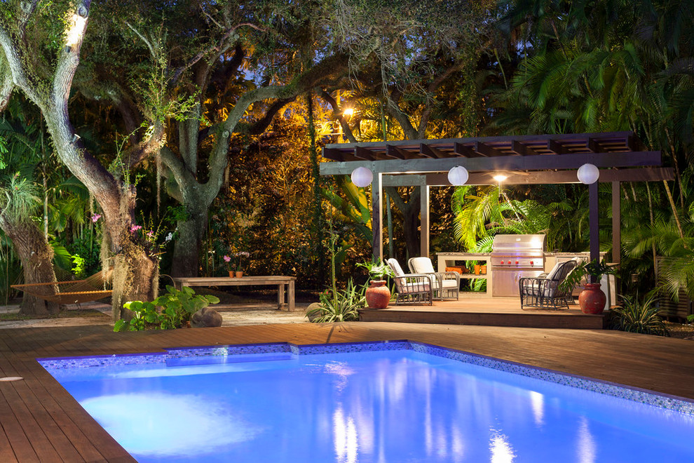 Diseño de piscina tropical grande en patio trasero con entablado