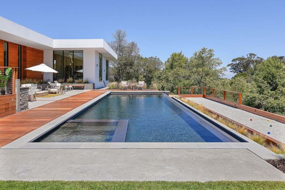 Идея дизайна: прямоугольный бассейн-инфинити на заднем дворе в современном стиле с джакузи и покрытием из бетонных плит