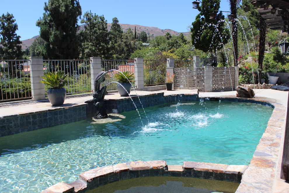 Idee per una piscina tradizionale a "C" di medie dimensioni e dietro casa con una vasca idromassaggio e pavimentazioni in pietra naturale