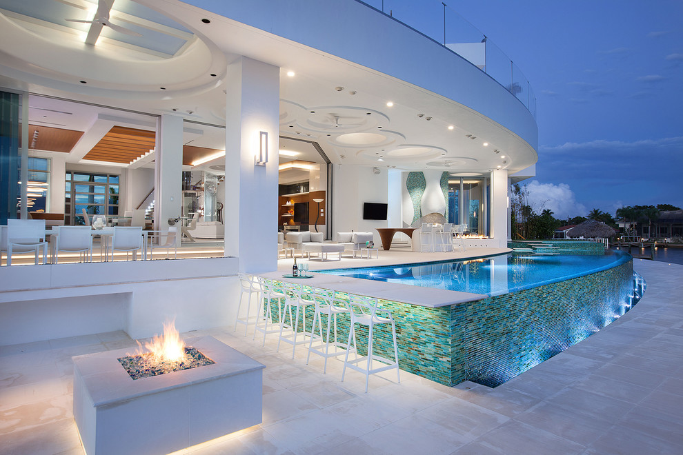 Contemporary back custom shaped infinity swimming pool with tiled flooring and a bar area.