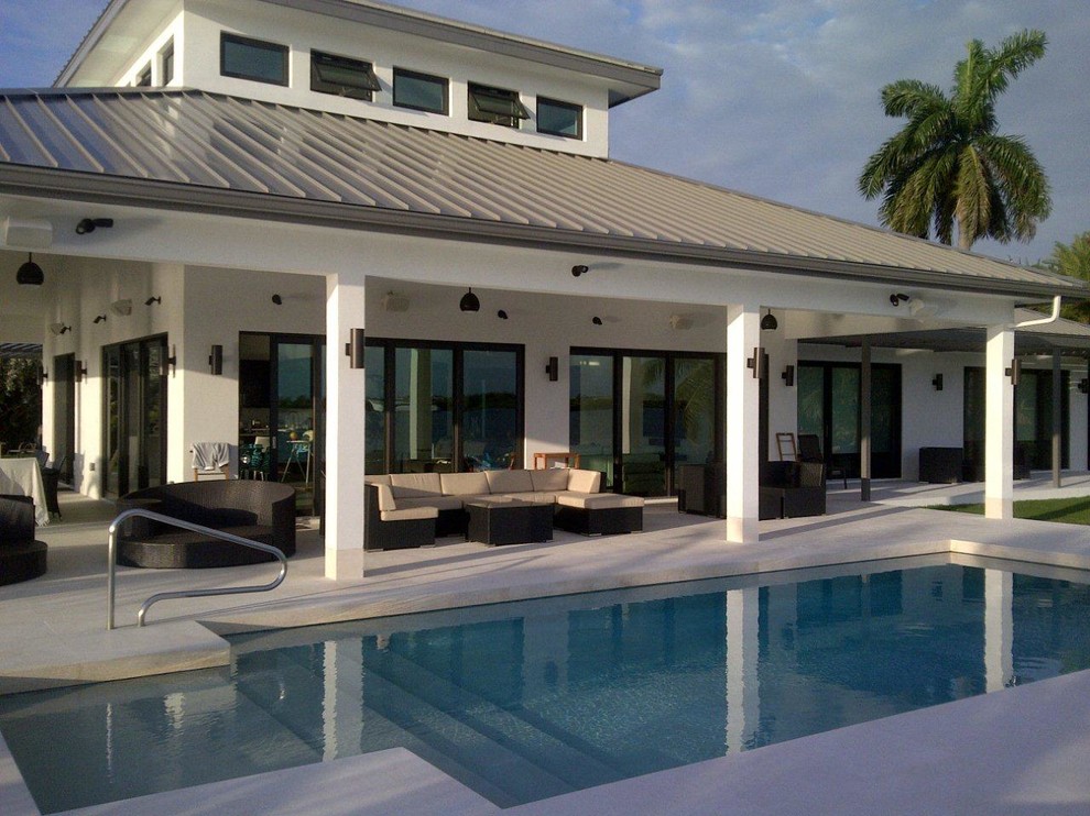 Imagen de piscina alargada extra grande rectangular en patio trasero con losas de hormigón
