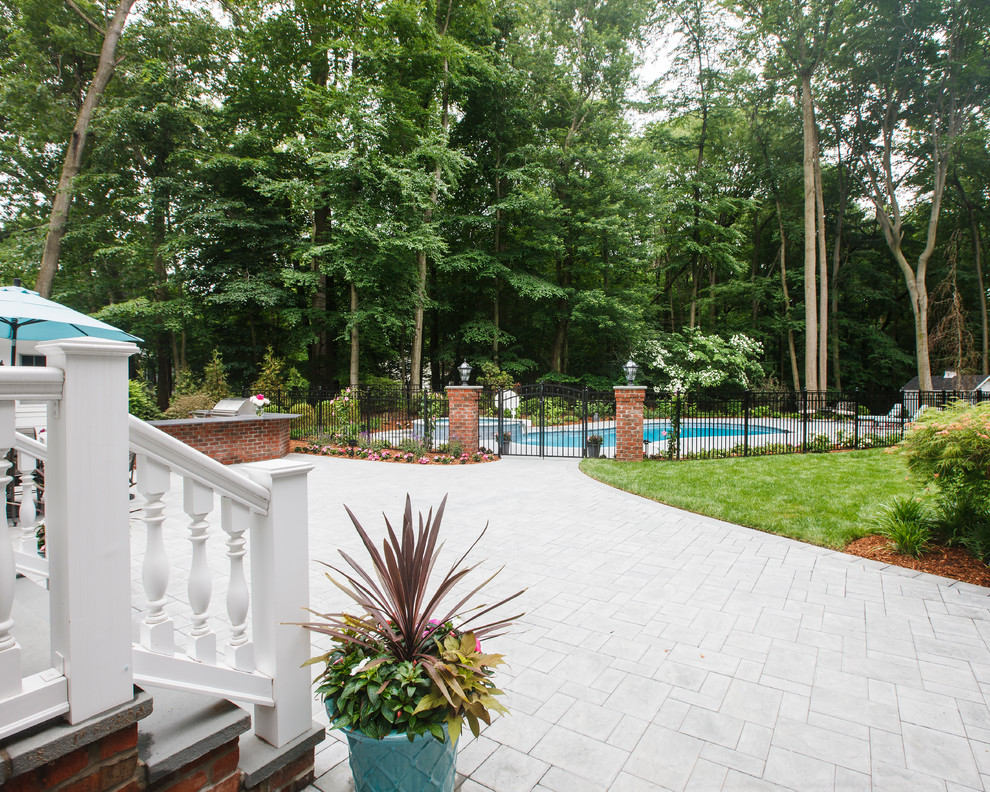 Diseño de piscina alargada tradicional de tamaño medio tipo riñón en patio trasero con adoquines de hormigón