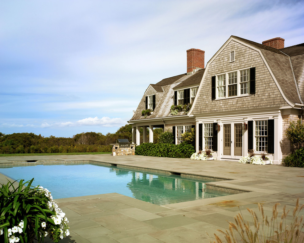 Exempel på en mellanstor klassisk rektangulär pool längs med huset, med naturstensplattor och spabad