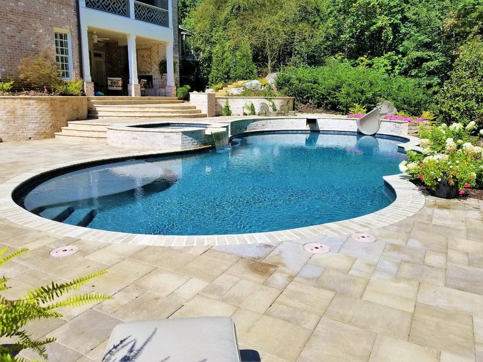 Источник вдохновения для домашнего уюта: большой естественный бассейн произвольной формы на заднем дворе в классическом стиле с водной горкой и мощением тротуарной плиткой