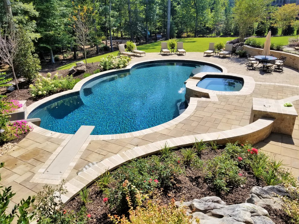 Ispirazione per una grande piscina naturale chic personalizzata dietro casa con un acquascivolo e pavimentazioni in cemento