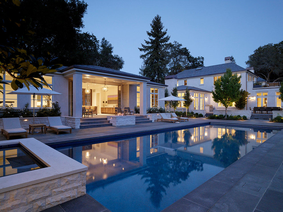 Diseño de casa de la piscina y piscina alargada tradicional renovada extra grande rectangular en patio trasero con adoquines de piedra natural