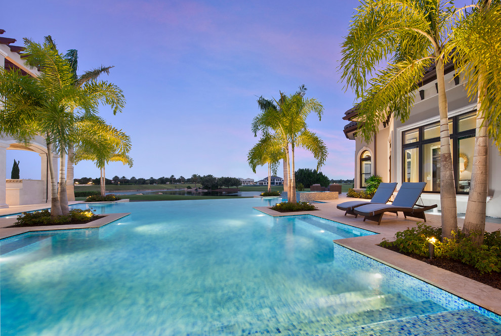 Imagen de piscina infinita mediterránea extra grande a medida en patio trasero con adoquines de piedra natural