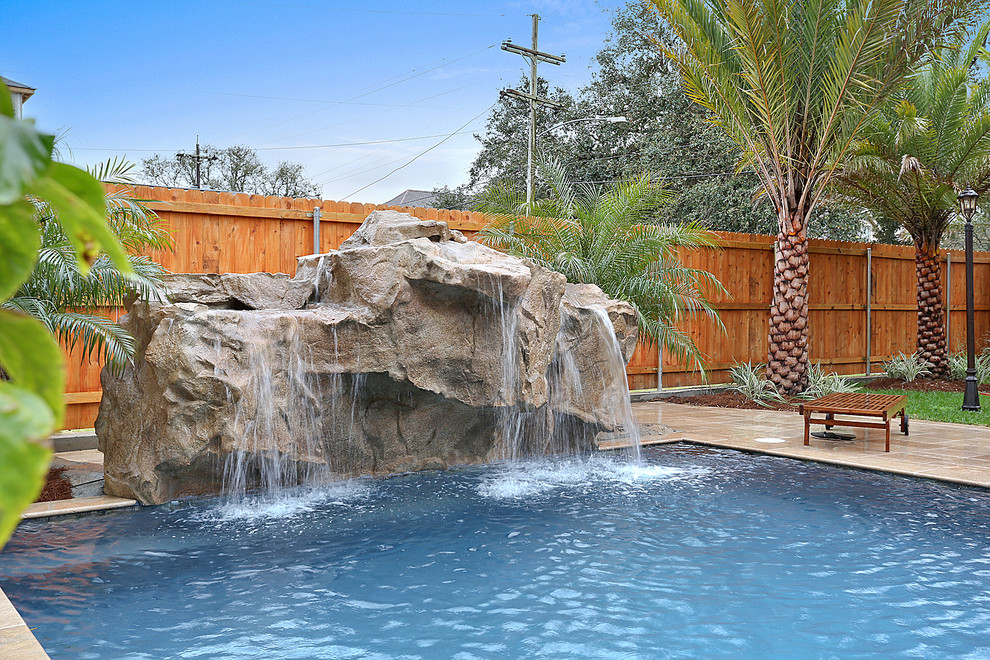Diseño de piscina con fuente alargada clásica de tamaño medio rectangular en patio trasero con suelo de hormigón estampado