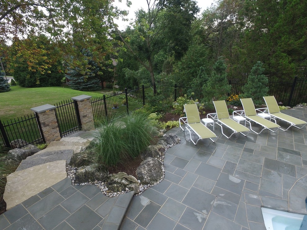 Foto di una piscina stile americano di medie dimensioni e dietro casa con fontane e pavimentazioni in pietra naturale