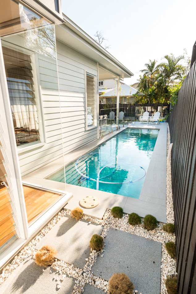 Diseño de piscina alargada nórdica de tamaño medio rectangular en patio lateral con suelo de baldosas