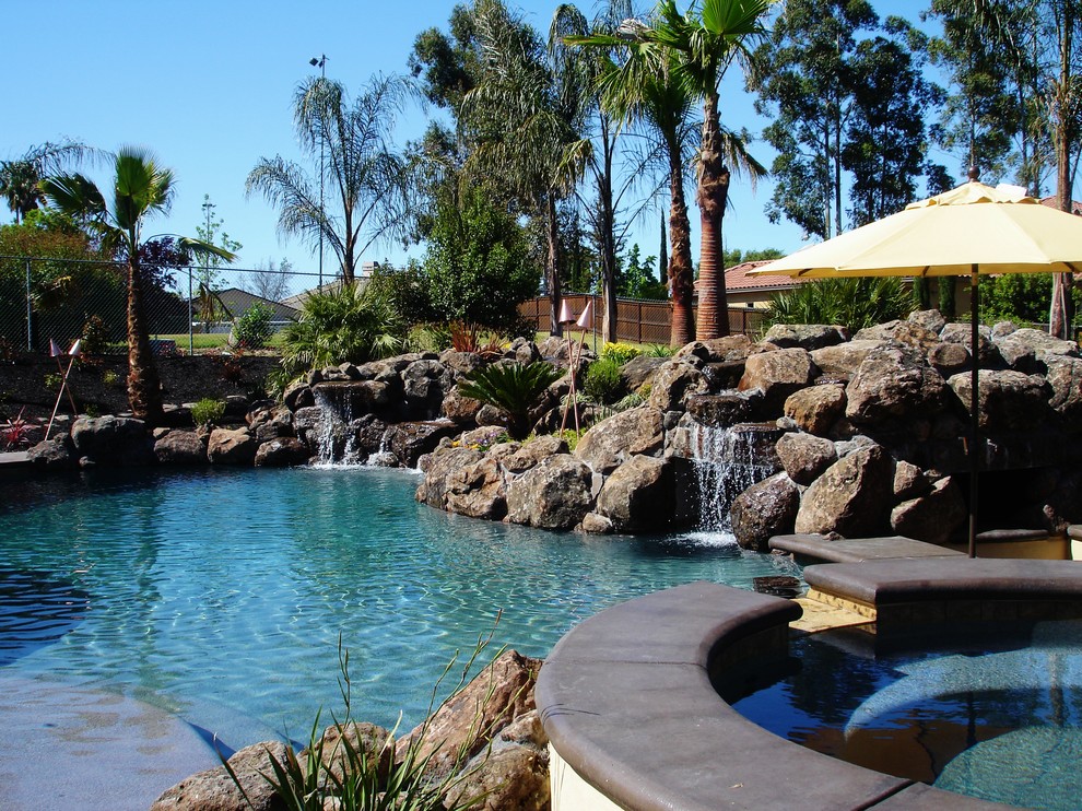 Diseño de piscina con fuente natural contemporánea de tamaño medio a medida en patio trasero con suelo de hormigón estampado