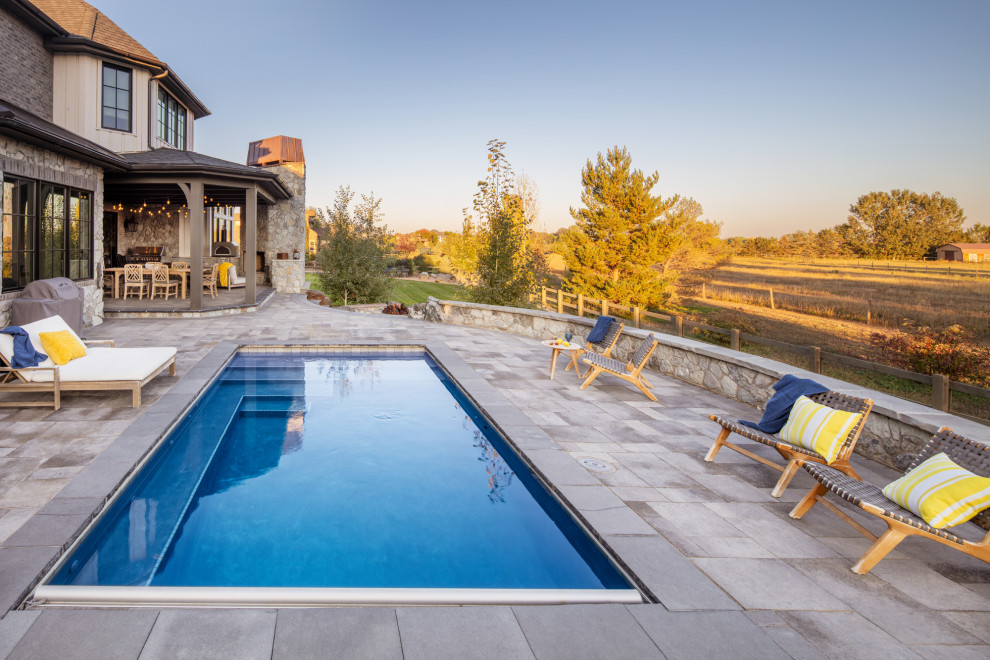 Foto de piscina alargada grande rectangular en patio trasero con paisajismo de piscina y adoquines de hormigón