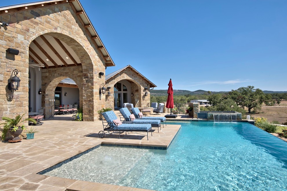 Modelo de piscina infinita tradicional renovada de tamaño medio rectangular en patio trasero con adoquines de piedra natural