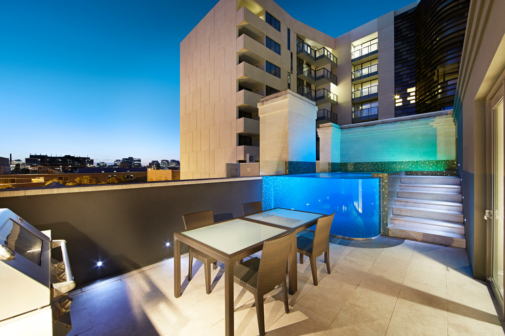 Réalisation d'une petite piscine sur toit hors-sol design rectangle avec des pavés en pierre naturelle.