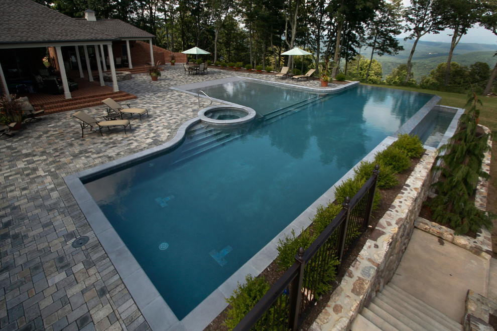 Modelo de piscinas y jacuzzis alargados modernos grandes en forma de L en patio trasero con adoquines de ladrillo