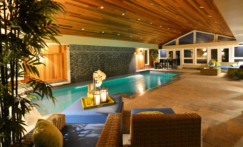 Diseño de casa de la piscina y piscina actual de tamaño medio rectangular en patio trasero con adoquines de piedra natural