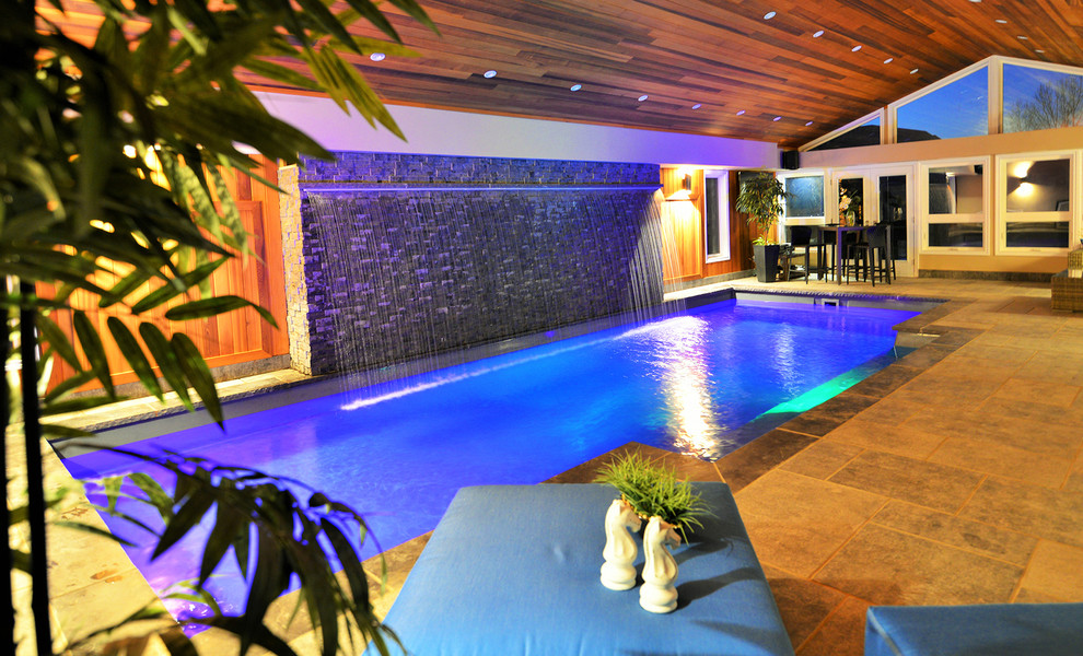 Modelo de casa de la piscina y piscina contemporánea de tamaño medio rectangular en patio trasero con adoquines de piedra natural