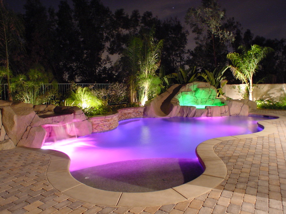 Großer Moderner Schwimmteich hinter dem Haus in individueller Form mit Wasserrutsche und Pflastersteinen in Los Angeles