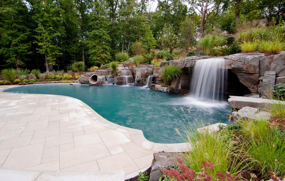 Aménagement d'une piscine naturelle exotique avec des pavés en pierre naturelle et un point d'eau.
