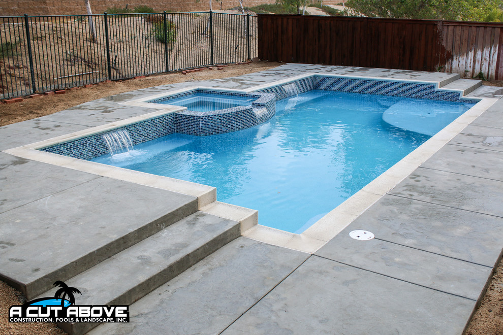 Foto de piscina tradicional de tamaño medio rectangular en patio trasero con suelo de hormigón estampado