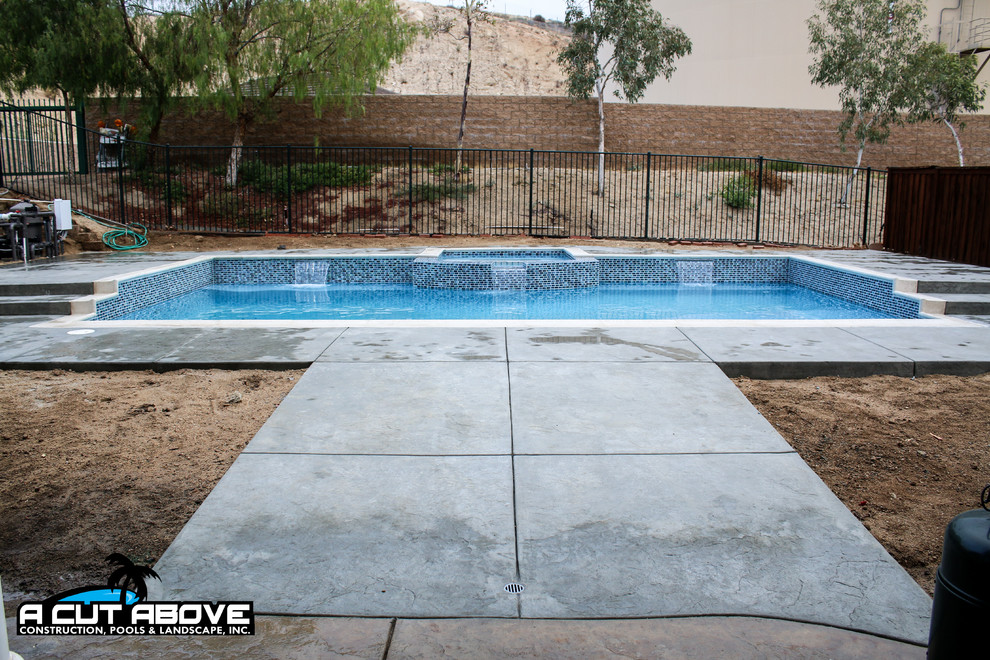 Immagine di una piscina chic rettangolare di medie dimensioni e dietro casa con cemento stampato