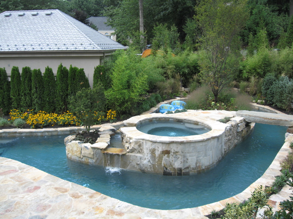 Esempio di un'ampia piscina naturale tradizionale personalizzata dietro casa con fontane e pavimentazioni in pietra naturale