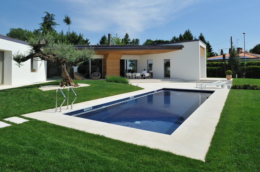 Ejemplo de piscina minimalista rectangular en patio trasero con losas de hormigón