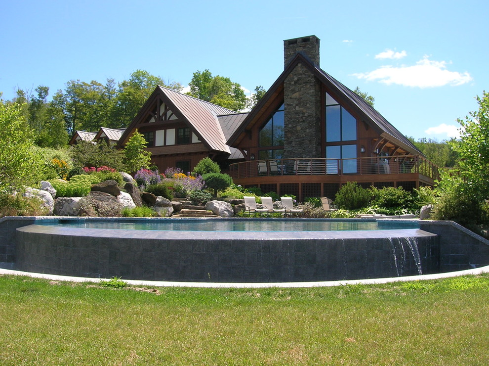 Ejemplo de piscina infinita de estilo americano de tamaño medio a medida en patio trasero con adoquines de hormigón