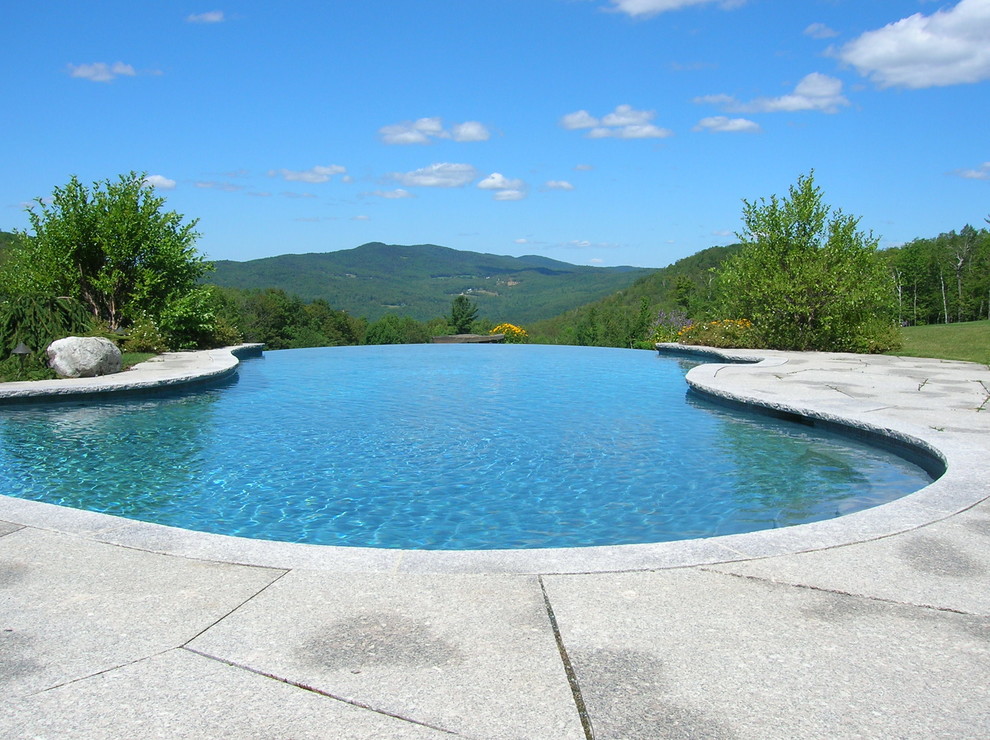 Immagine di una piscina a sfioro infinito american style personalizzata di medie dimensioni e dietro casa con pavimentazioni in cemento