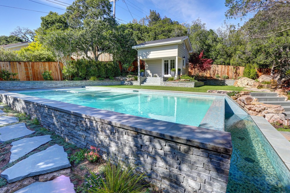 Immagine di una piccola piscina a sfioro infinito tradizionale rettangolare dietro casa con una dépendance a bordo piscina e pavimentazioni in pietra naturale
