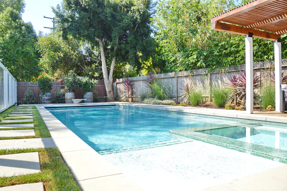 Imagen de piscinas y jacuzzis alargados tradicionales rectangulares en patio trasero con adoquines de hormigón