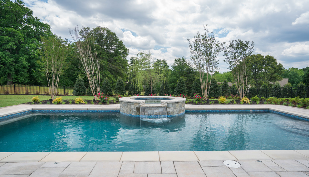 Esempio di una grande piscina monocorsia chic rettangolare dietro casa con una vasca idromassaggio e pavimentazioni in cemento
