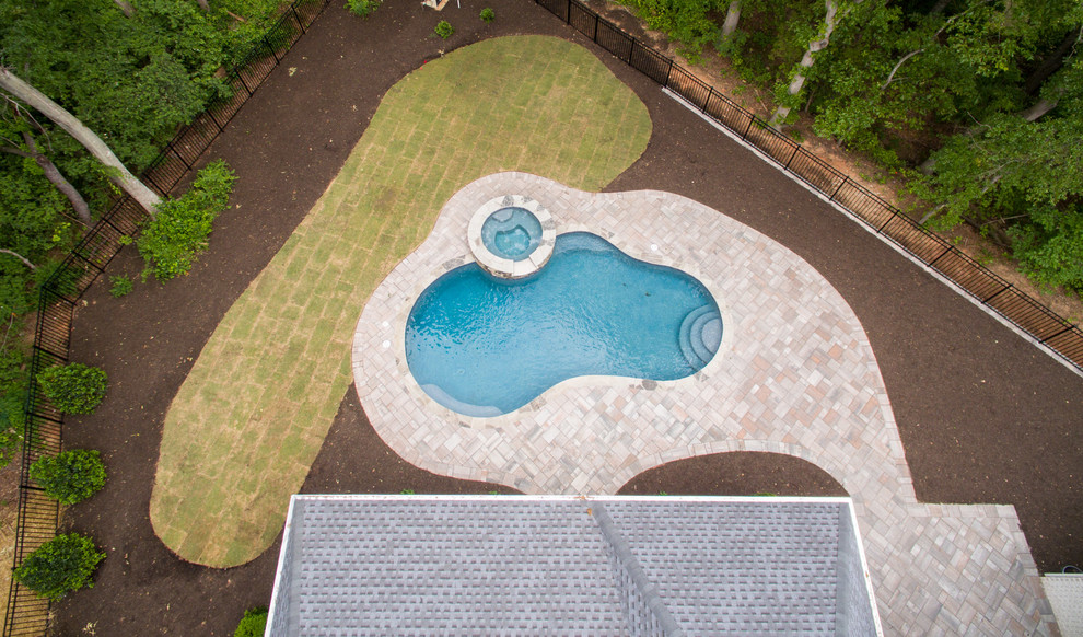 Diseño de piscinas y jacuzzis alargados de estilo americano de tamaño medio tipo riñón en patio trasero con suelo de baldosas