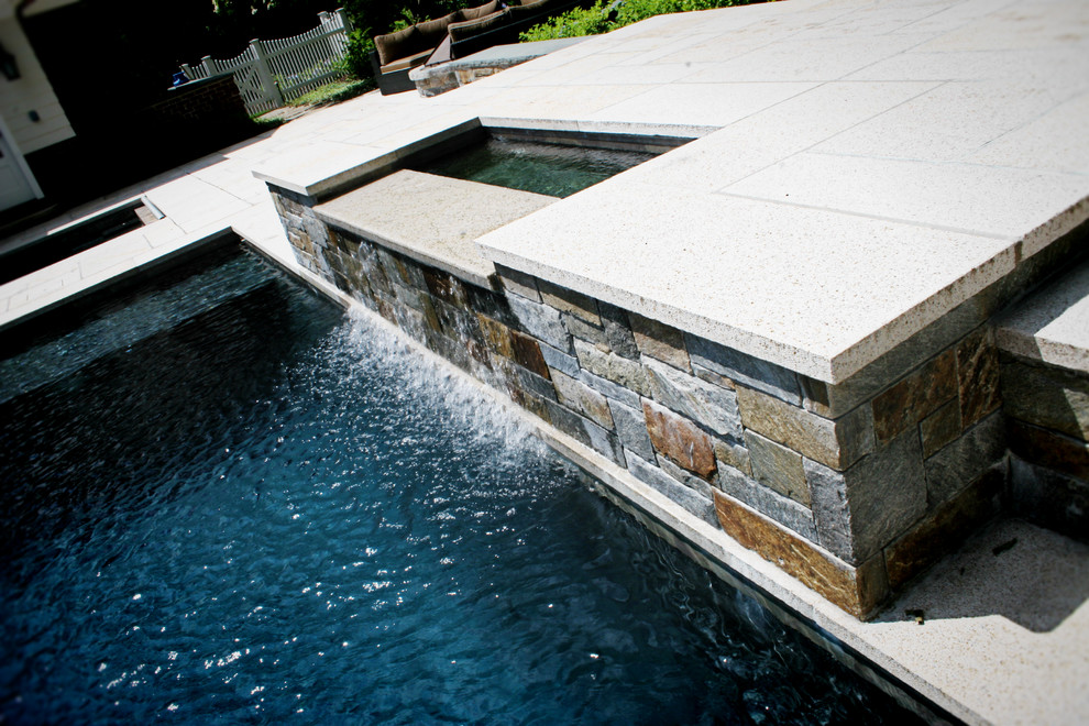 Inspiration for an expansive contemporary back custom shaped swimming pool in New York with a water feature.