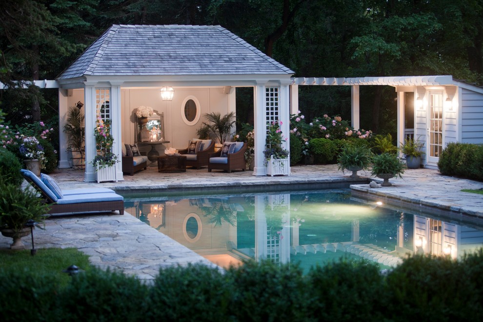 This is an example of a traditional rectangular swimming pool in New York with natural stone paving and a pool house.
