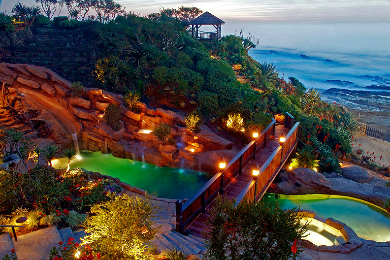 Idee per un'ampia piscina tropicale personalizzata dietro casa con un acquascivolo e cemento stampato