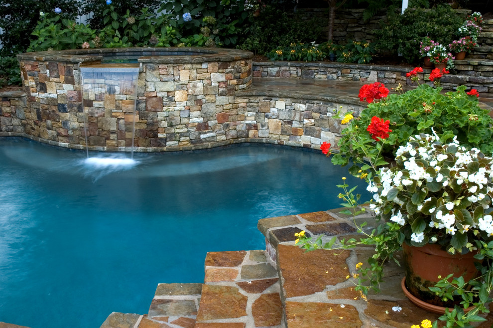 Aménagement d'une piscine naturelle et arrière classique de taille moyenne et sur mesure avec un bain bouillonnant et des pavés en béton.