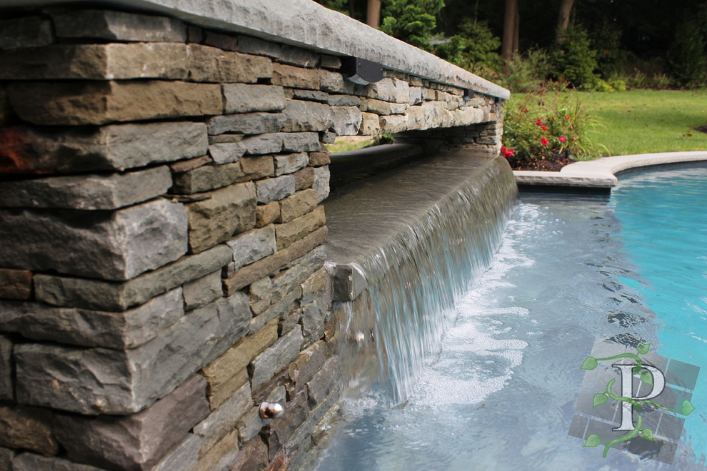 Bild på en mellanstor funkis anpassad pool på baksidan av huset, med en fontän och naturstensplattor