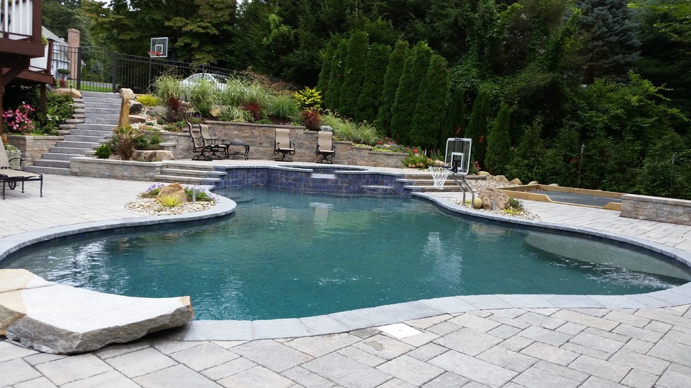 Imagen de piscina tradicional de tamaño medio tipo riñón en patio trasero con adoquines de piedra natural