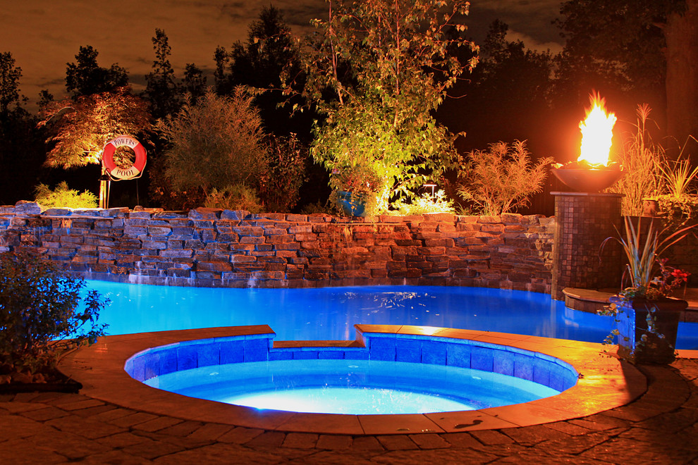 Diseño de piscina grande en patio trasero con adoquines de piedra natural