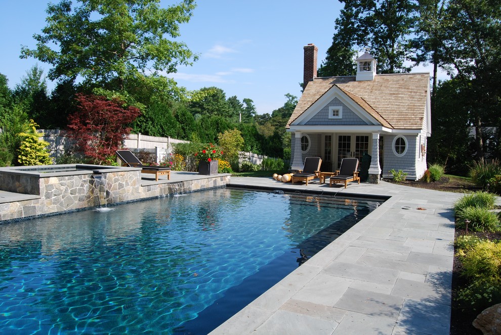 Modelo de piscinas y jacuzzis alargados clásicos de tamaño medio rectangulares en patio trasero con adoquines de piedra natural