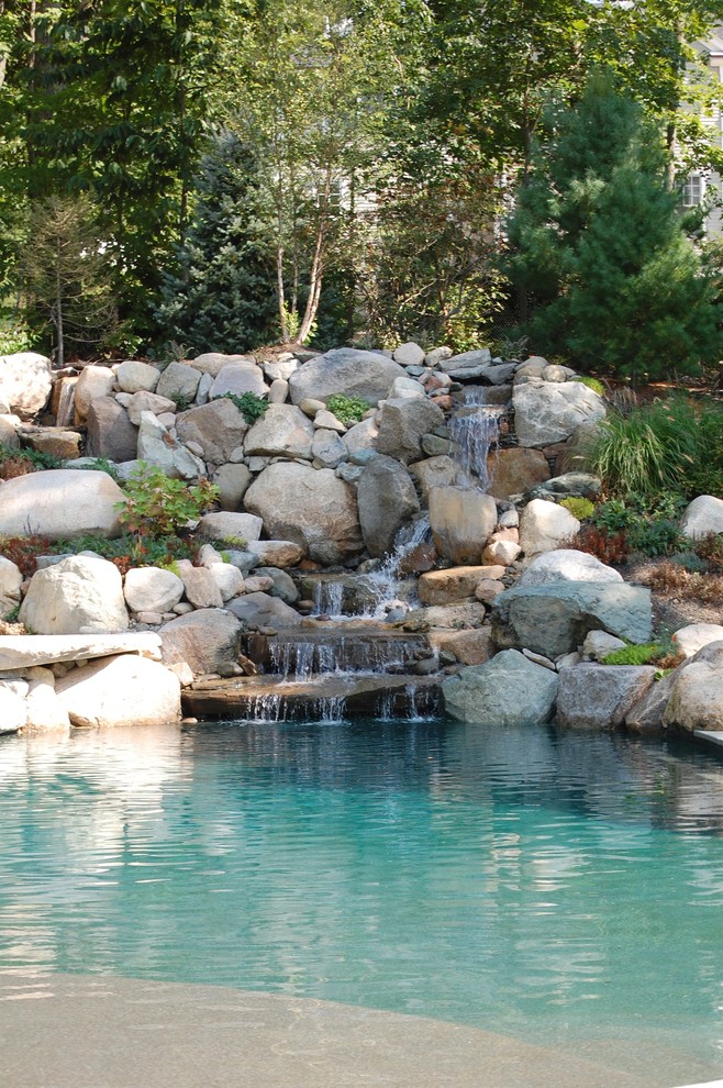 Imagen de piscina con fuente alargada tradicional de tamaño medio a medida en patio trasero con adoquines de hormigón