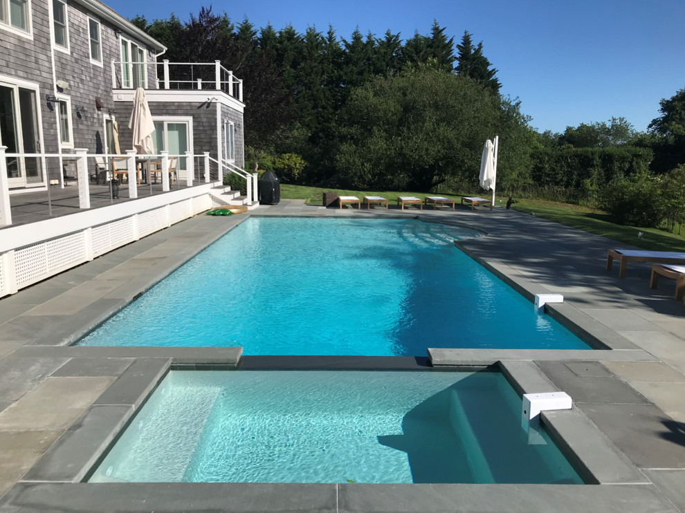 Ispirazione per una grande piscina monocorsia design rettangolare dietro casa con pavimentazioni in pietra naturale