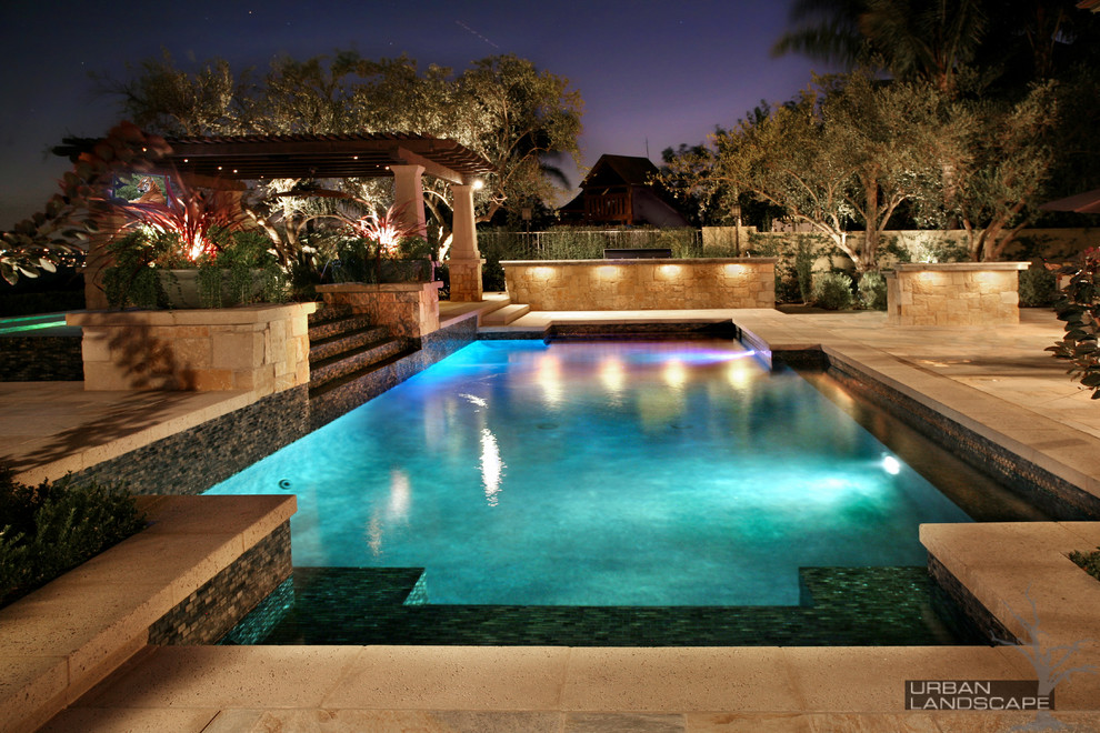 Idée de décoration pour une grande piscine à débordement et arrière méditerranéenne rectangle avec un bain bouillonnant et des pavés en pierre naturelle.