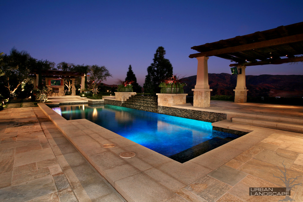 Imagen de piscinas y jacuzzis infinitos mediterráneos grandes rectangulares en patio trasero con adoquines de piedra natural